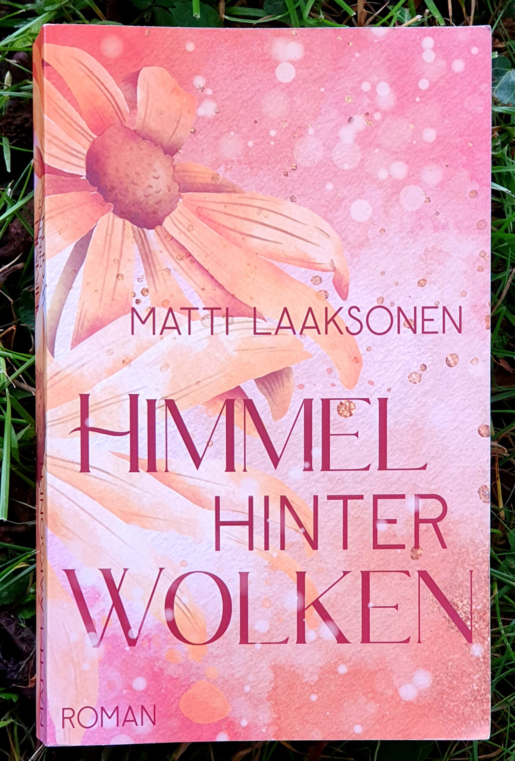 Buchdeckel in rosa und orange Tönen, ein große Blumen mit Wasserfarbeneffekt, in eleganten Buchstaben: Matti Laaksonen, Himmel hinter Wolken, Roman.